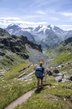 Mountaineer on hiking trail in mountain landscape, descent at Col du Louvie, view of the summit of