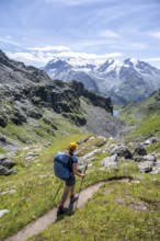 Mountaineer on hiking trail in mountain landscape, descent at Col du Louvie, view of the summit of