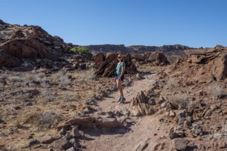 Tourist on a hiking trail in a barren landscape, visiting the rock engravings of Twyfelfontein,