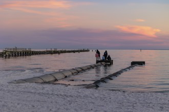 Young adults ignoring danger sign while fishing and playing on storm drain culvert in Long Beach,