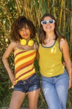 Two female friends posing together in a lush bamboo forest, soaking up the sun and embracing the