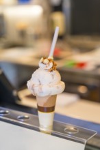 Delicious ice cream topped with nuts and chocolate, served in a waffle cone, sitting enticingly on