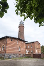 Lighthouse Darßer Ort, brick lighthouse next to a historic building, surrounded by trees under a