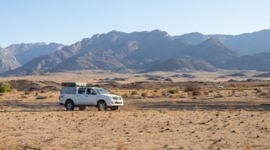 Tourist with off-road car on a sandy track, rock formation, Brandberg, Damaraland, Namibia