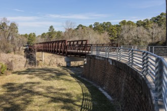 Steel bridge along paved biking and walking trail in Cypress Creek Park at Timber Lane in Spring,