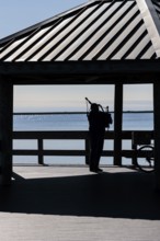 Silhouette of a man playing bag pipes under a pavilion on Halstead Bayou in Gulf Islands National