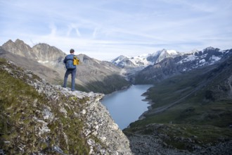Mountaineer on the summit of Mont de la Blana, view of a blue mountain lake, Lac des Dix reservoir,