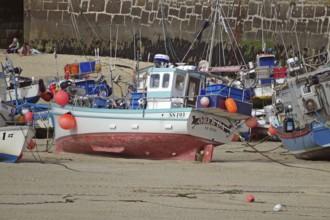 Fishing boats in the harbour on the dry dock, surrounded by a harbour wall and sandy bottom, St