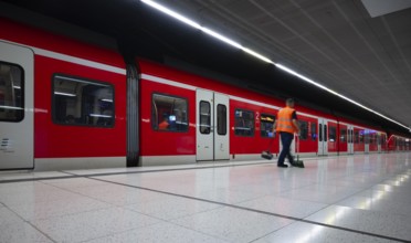 Underground arriving S-Bahn, train, class 420 in traffic red, cleaner cleans platform, cleaning,