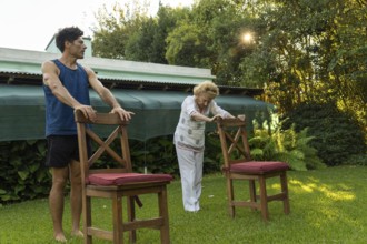 Senior woman practicing physical therapy exercises with the help of her personal trainer, using