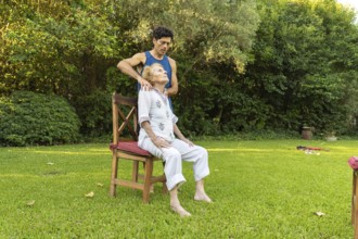 Physiotherapist is giving a shoulder massage to a senior woman sitting on a chair in a peaceful