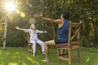 Senior woman practicing seated exercises with the assistance of a physiotherapist in a green