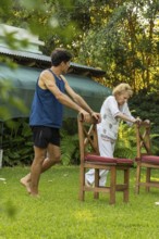 Young male physiotherapist assisting a senior woman performing rehabilitation exercises using