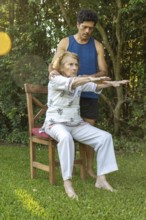 Senior woman practicing seated stretches with the assistance of a physiotherapist in a peaceful