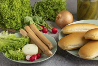 Various ingredients on plates, including salad, sausages and bread rolls