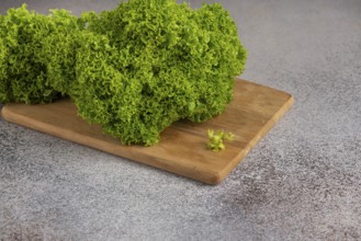 Green salad on a wooden board on a grey background