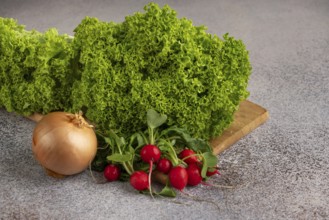 Green salad, onion and radish on a wooden board