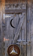 Weathered wood door to outhouse with moon cut-out