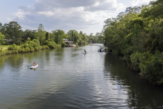 Young women paddleboarding on the Magnolia River in Magnolia Springs, Alabama