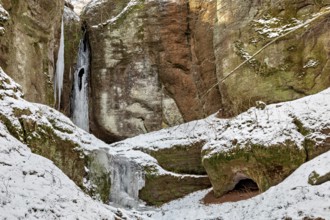 Snow-covered rocks with icicles and a small cave in winter, the Dragon Gorge near Eisenach in
