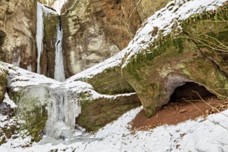 Snow-covered rocks with icicles and a small cave, the Dragon Gorge near Eisenach in Thuringia