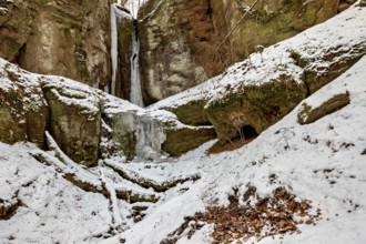 Snow-covered rocky landscape with icicles and a small cave, the Dragon Gorge near Eisenach in