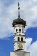 Elegant baroque tower with onion dome roof and clock, surrounded by blue clouds, The town of