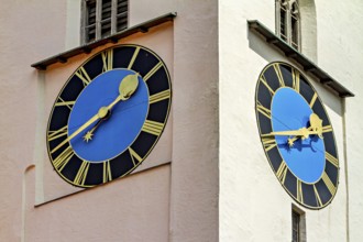 Two large, colourful clocks on a tower show different times in a historical setting, tower clock in