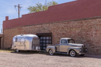 Silver painted classic fort pickup truck and a stainless steel Airstream camper travel trailer
