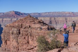 Visitors climb on rock formation rising above the canyon at Guano Point in Grand Canyon West near