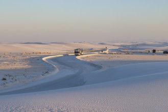 Motorhome being driven on cleared road through the white gypsum dunes at White Sands National Park