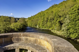 Stone bridge with a view of a river and green hills in the background, view from the historic Werra