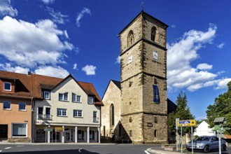 Central church tower in the village with surrounding buildings and streets under a blue sky, The