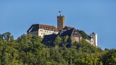 Castle with striking tower rises above green forests, Wartburg Castle near Eisenach in Thuringia