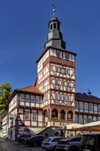 Half-timbered tower and historic buildings with parked cars under a blue sky, The town hall of