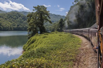 Steam from the Great Smoky Mountains Railroad hangs in the air as the train rounds a curve through