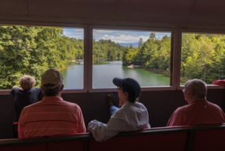 Great Smoky Mountains Railroad passengers looking out the windows of the open air train car while