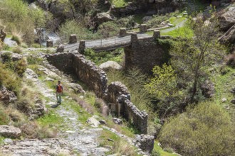 At village Busquistar, hiking path in the gorge of river Trevelez, hiking woman, bridge, Sierra