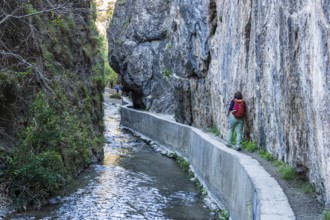 Woman on narrow hiking path Los Cahorros de Monachil, along the Rio Monachil river, narrow path in