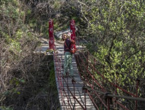 Woman on suspension bridge, hiking path Los Cahorros de Monachil, along the Rio Monachil river,