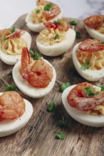Boiled eggs stuffed with yolk and seasoned with mayonnaise, stuffed eggs with shrimp, on a wooden
