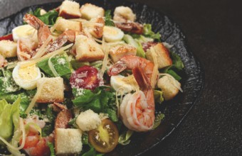 Caesar salad with tiger prawns, shrimp salad, lettuce leaves, quail eggs, cherry tomatoes, parmesan