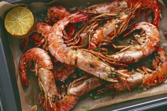 Juicy grilled shrimp, placed on a baking sheet lined with parchment paper, garnished with herbs and