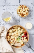 Caesar salad in a paper container, take it on the way, with sauce and croutons, on the table,