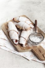 Bagels with filling, sweet pastries, sprinkled with powdered sugar, on a wooden board, dessert,