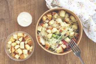 Caesar salad in a paper container, take it on the way, with sauce and croutons, on the table,