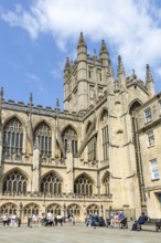 People relaxing on benches Bath Abbey church yard, city of Bath, north east Somerset, England, UK