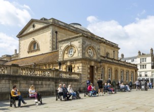People relaxing next to Roman Baths building, Abbey church yard, city of Bath, north east Somerset,