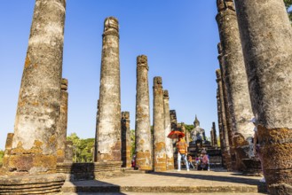Visitors between columns in the historic Buddhist temple complex Wat Mahathat, historical park,