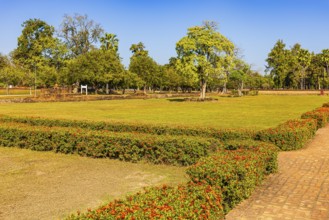 Historical park with green grass and red honeysuckle hedges, Sukhothai, Sukhothai province,
